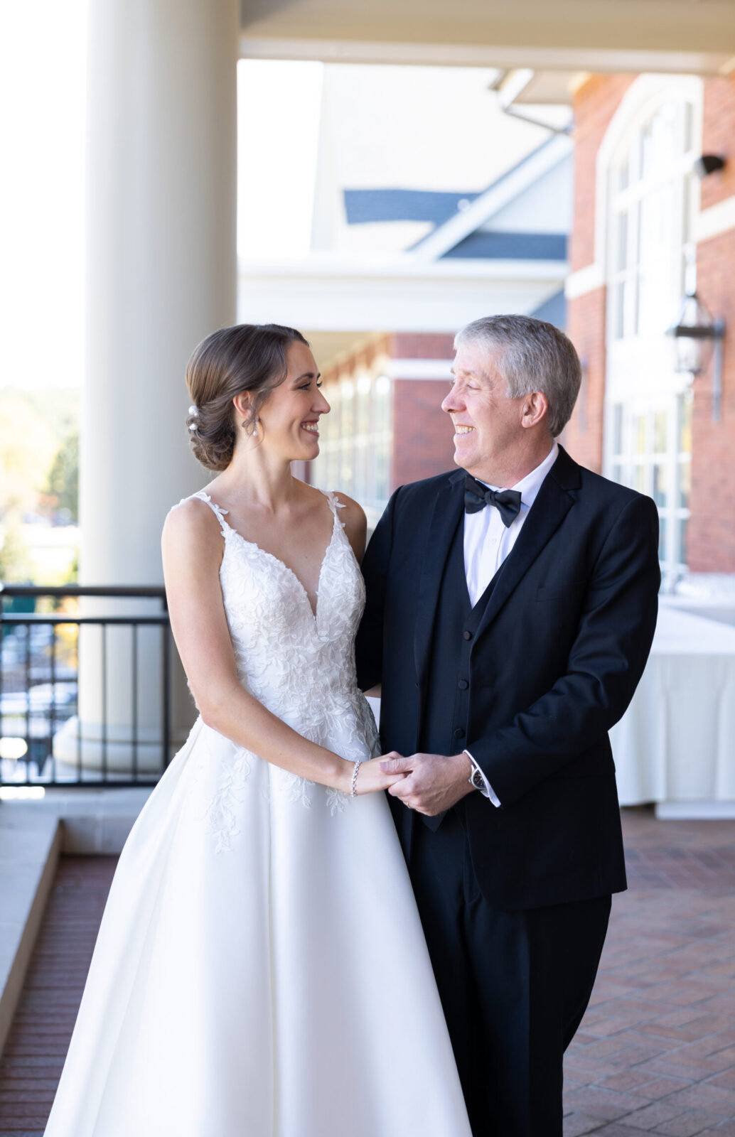 Father of Bride in black tux smiles at bride in flowing classic white sweetheart neckline wedding gown in her durham wedding 
