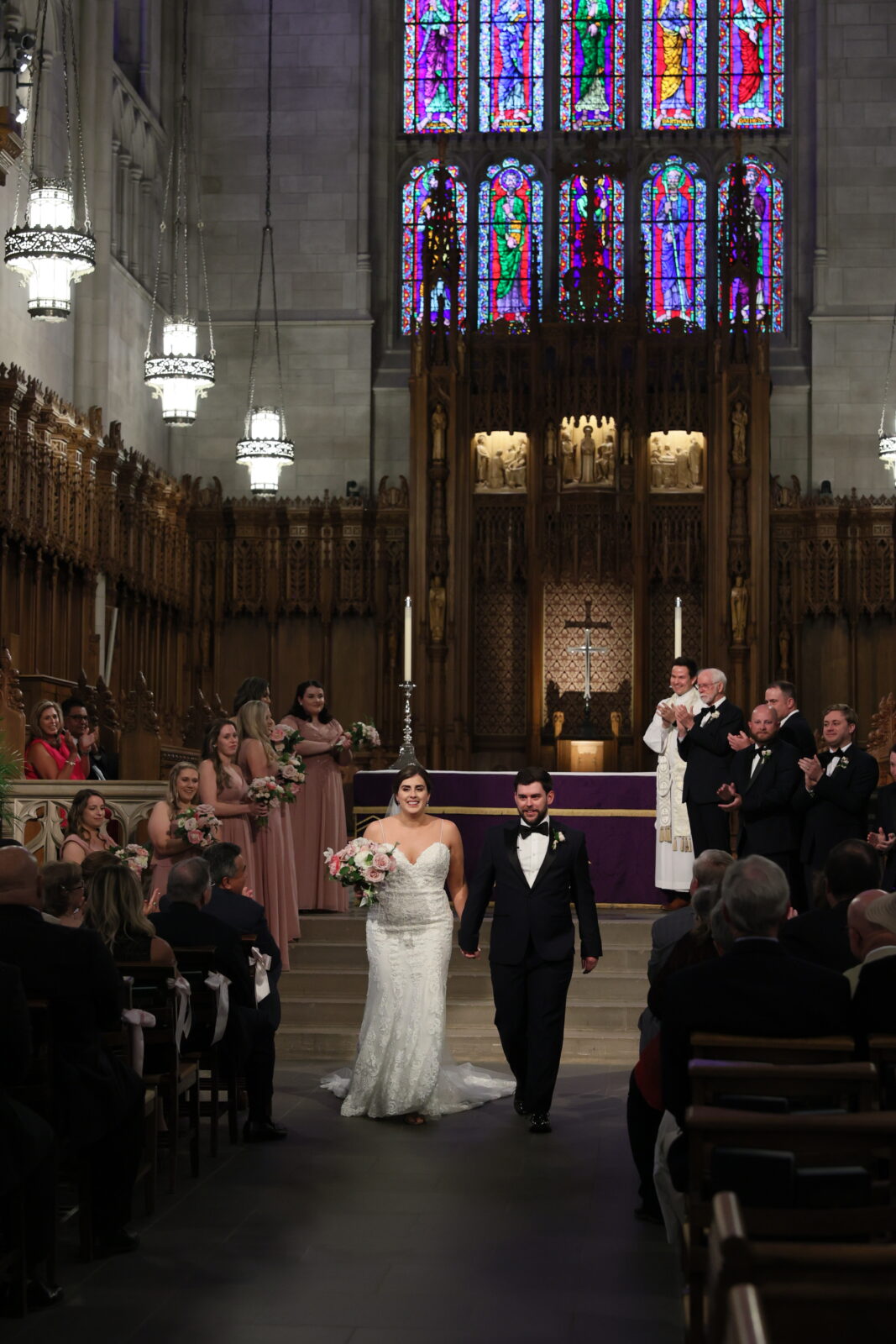 Bride in mermaid sweetheart wedding dress holding off white and blush bouquet  next to groom in black tux at duke chapel in Durham NC