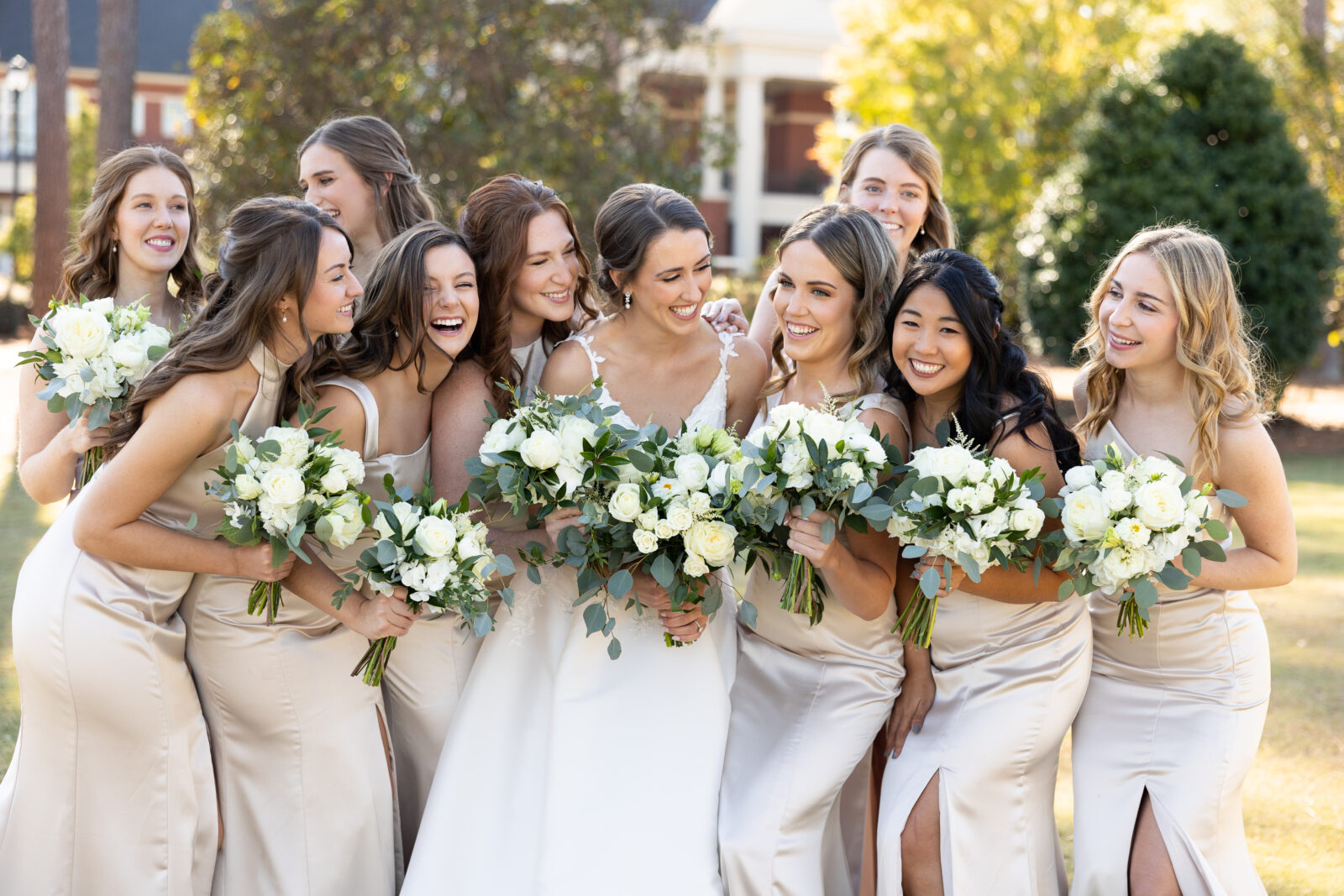 Bride in elegant white plunging v neck wedding dress walking with bridesmaids in champagne bridesmaid dresses 