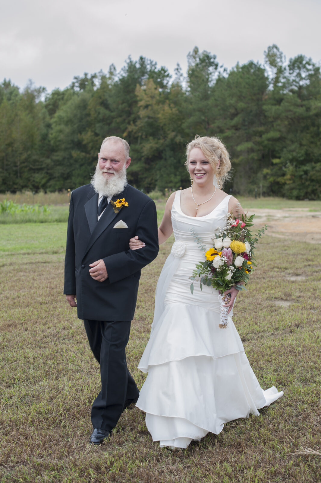 Bride walking down the asile with father in a mermaid pulled silk dress in wilmington nc